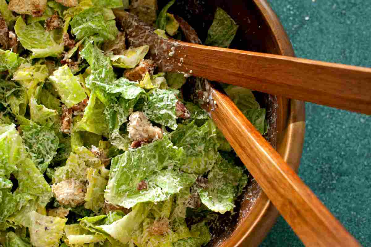 Caesar Salad in una ciotola con mestoli in legno
