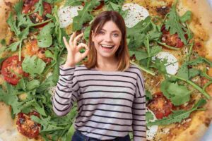 donna fa ok con le mani davanti a una pizza