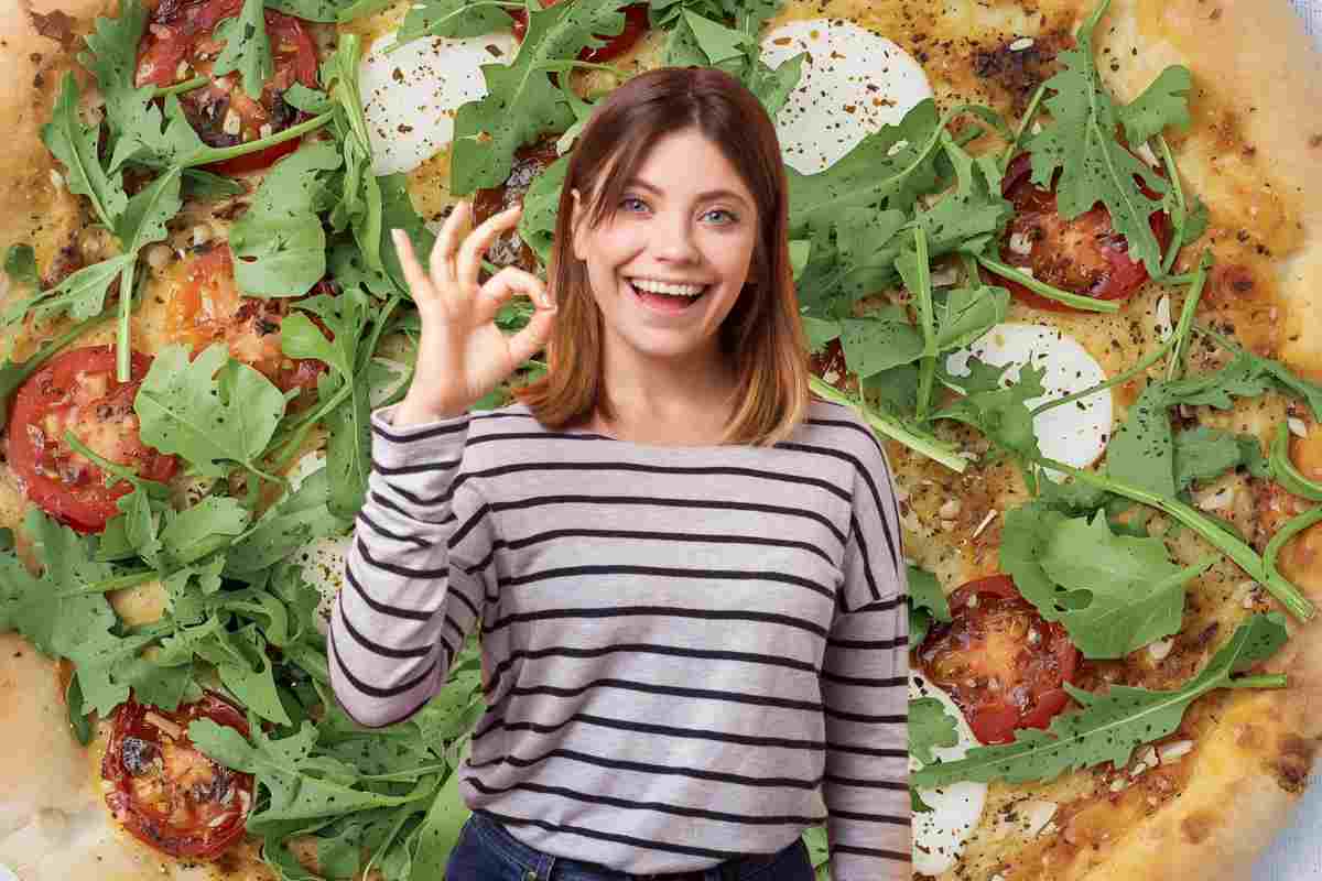 donna fa ok con le mani davanti a una pizza