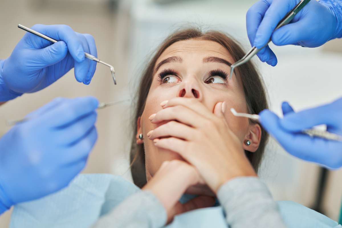 donna si copre la bocca mani di dentisti con strumenti